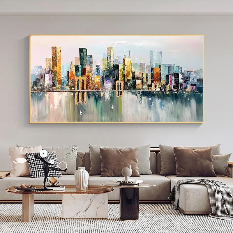May include: A painting of a cityscape with colorful buildings reflected in the water. The buildings are painted in a variety of shades of blue, green, yellow, and orange. The water is a light blue with white highlights.