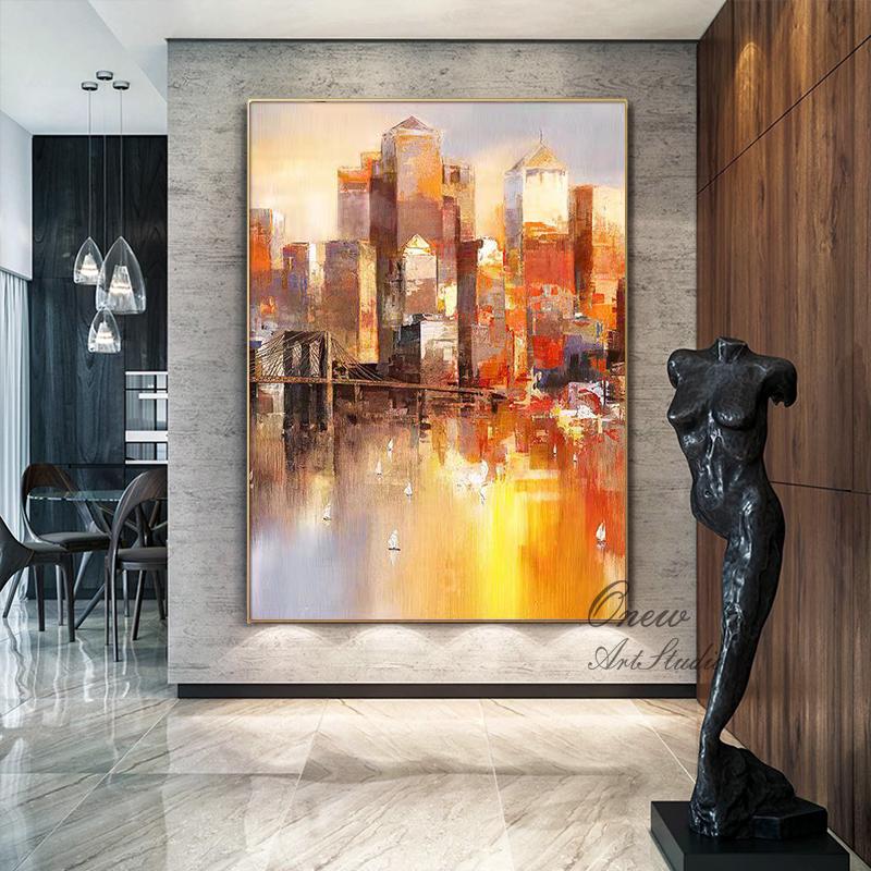 May include: Abstract painting of a cityscape with a bridge in the foreground. The city is painted in warm colors, including yellow, orange, and red. The bridge is painted in a darker color, and the water is painted in a light blue color. The painting is framed in a gold frame.
