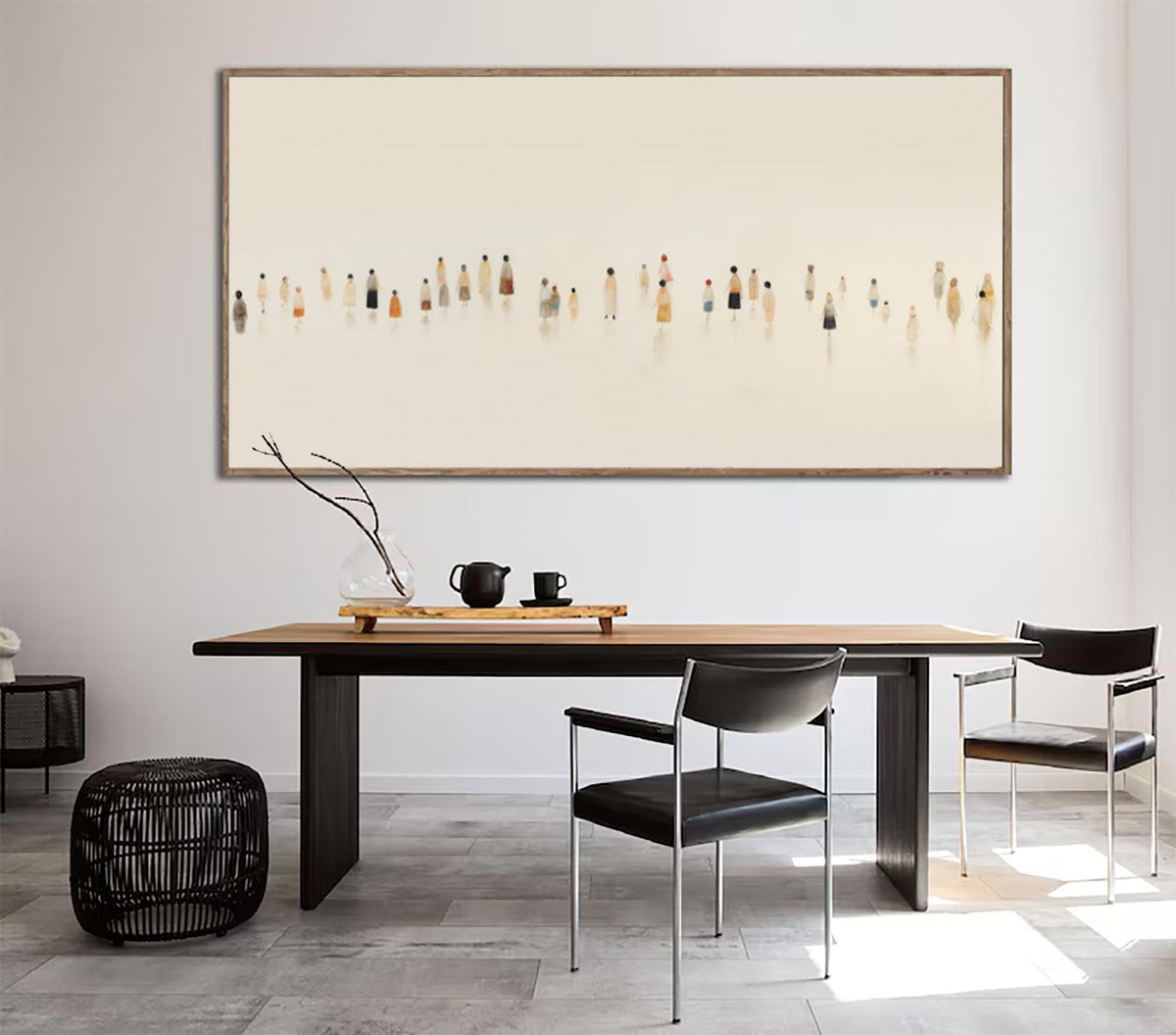 May include: A large framed artwork depicts a minimalist scene of numerous figures in various colors against a light background. The artwork hangs above a wooden dining table with black chairs. A black woven ottoman and a side table are also in the room.