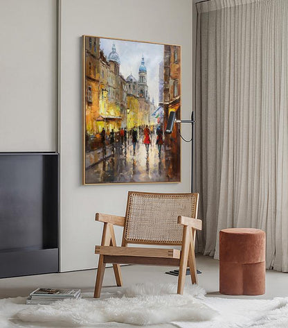 May include: A painting of a city street scene with buildings, people walking, and a church in the background. The painting is done in a realistic style with a warm color palette.