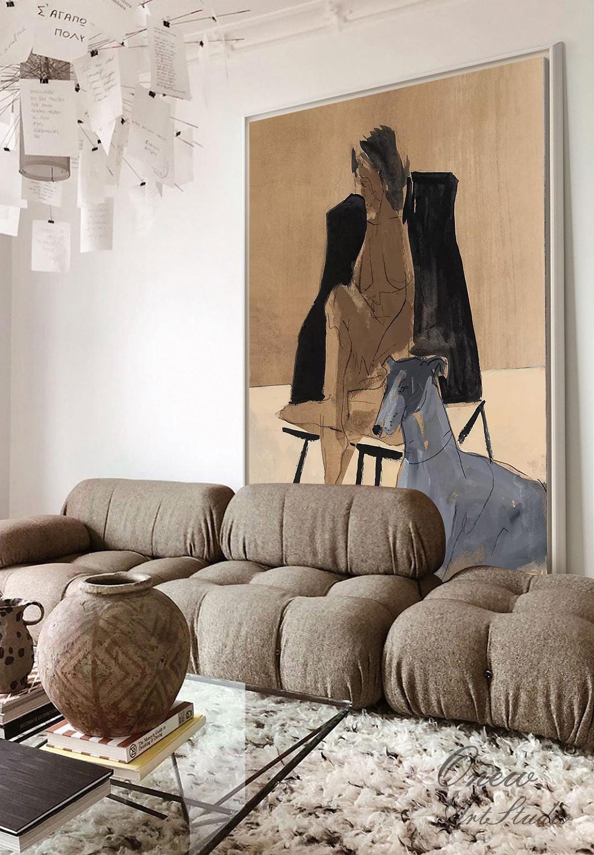 May include: A large abstract painting of a nude woman sitting on a chair with a greyhound dog beside her. The painting is in a living room setting with a brown couch and a glass coffee table.