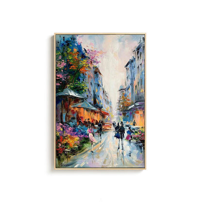 May include: Oil painting of a European street scene with buildings, shops, and people. The artwork features a vibrant color palette with blues, oranges, pinks, and greens. The painting is framed in a gold-colored frame.