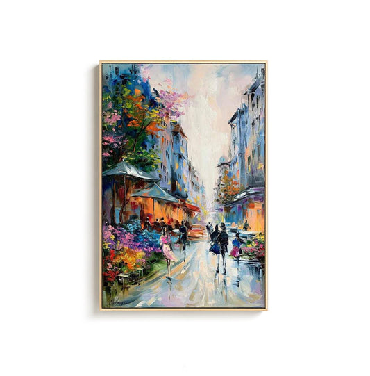 May include: Oil painting of a European street scene with buildings, shops, and people. The artwork features a vibrant color palette with blues, oranges, pinks, and greens. The painting is framed in a gold-colored frame.