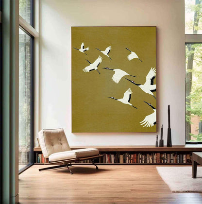May include: A large rectangular wall art piece featuring a mustard yellow background with a flock of white cranes in flight. The birds are depicted with black wingtips and red crowns, arranged in a dynamic diagonal composition across the canvas.