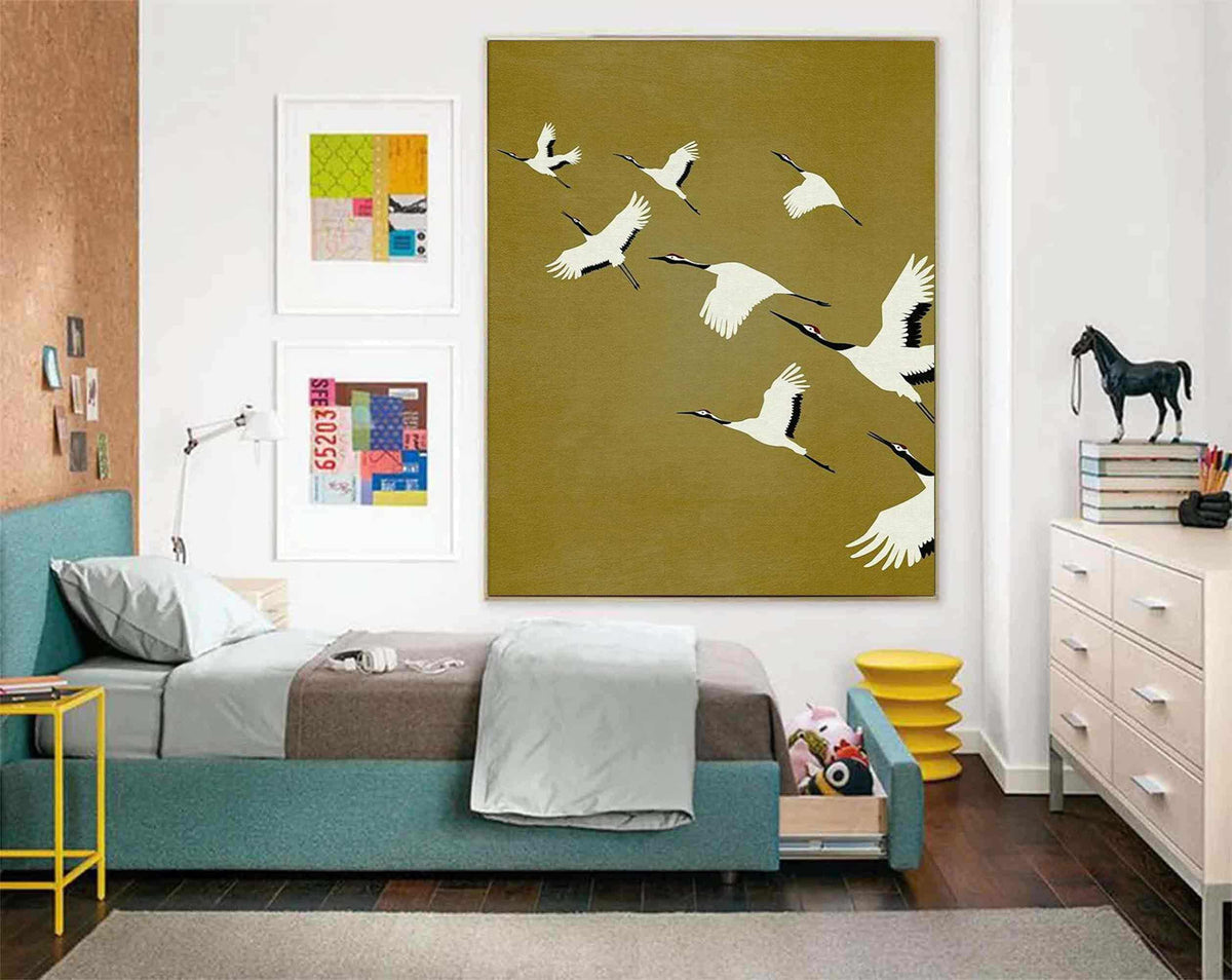 May include: A large rectangular wall art piece featuring a flock of white cranes with black wingtips and red crests flying across a solid olive green background. The painting is displayed in a bedroom above a teal upholstered bed frame.
