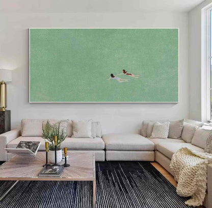 May include: A painting of two people swimming in a green body of water. The painting is framed and hanging on a white wall above a light gray sectional sofa.