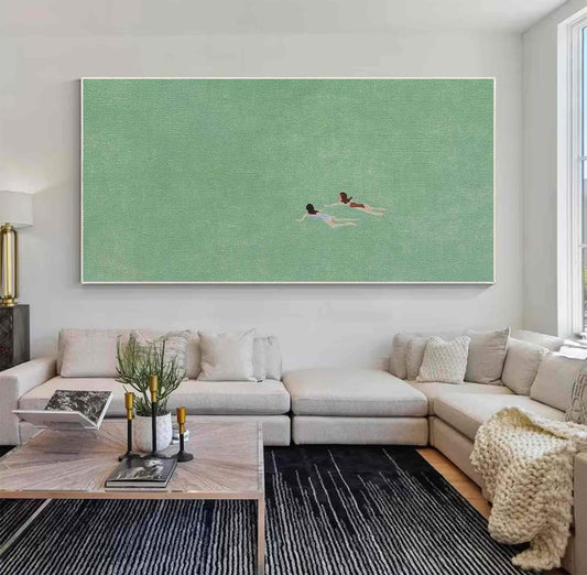 May include: A painting of two people swimming in a green body of water. The painting is framed and hanging on a white wall above a light gray sectional sofa.