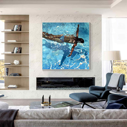 May include: A large framed painting depicts a swimmer underwater in a pool. The artwork features a person with dark skin, wearing blue swim trunks, and swimming with one arm extended. The water is a vibrant blue with light reflections.