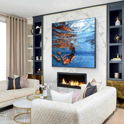 May include: A square wall art print featuring an underwater scene of a person swimming in blue water with light reflections on the surface. The artwork displays vibrant shades of blue, orange, and white, capturing the motion of a swimmer.