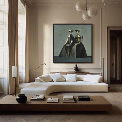 May include: A modern living room featuring a large abstract painting with geometric figures in a black frame. A white curved sofa with square pillows sits in front of a wooden coffee table with books and a black vase. The room has beige walls and hardwood floors.
