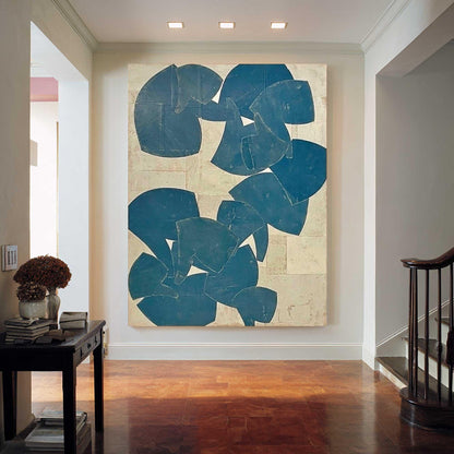 May include: Large abstract painting with blue shapes on a neutral background. The artwork is displayed in a hallway with hardwood floors and a dark side table. The painting's design features overlapping, irregular forms.
