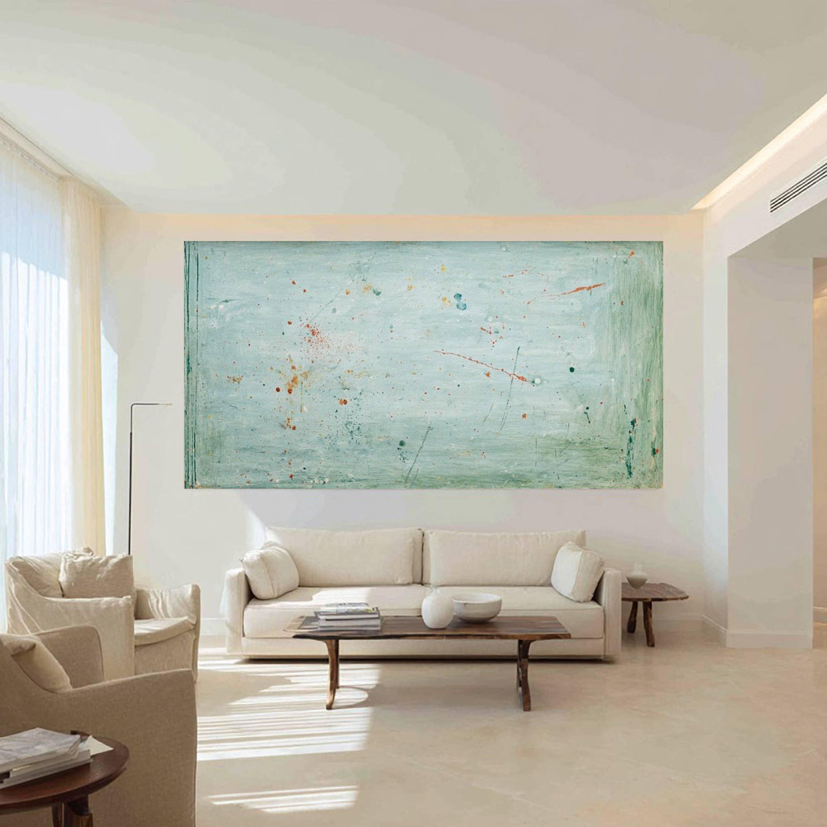 May include: An abstract painting with a light blue background and splashes of orange, red, and dark blue. The artwork is rectangular and mounted on a white wall above a cream-colored sofa. The room has a modern design with neutral tones.