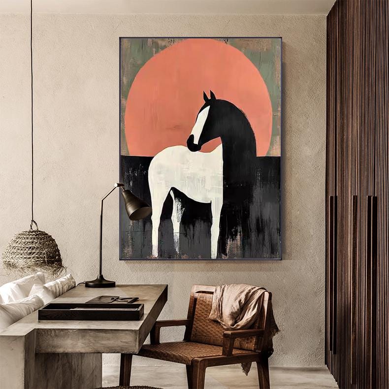 May include: Abstract art print of a horse. The horse is white and black, set against a large orange circle and a dark background. The artwork is framed and mounted on a wall in a room with a desk and chair.