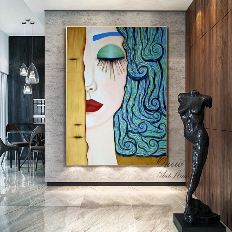 May include: A large framed painting of a woman's face, with one side in gold and the other in shades of blue and green. The woman has red lips and long eyelashes. A black sculpture of a female torso stands nearby.