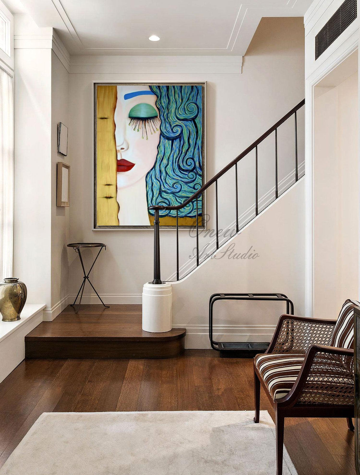 May include: An abstract painting of a woman's face with a side profile. The artwork features a vibrant color palette, including red lips, blue hair, and a green eye. The painting is displayed in a well-lit hallway with a staircase and a striped chair.