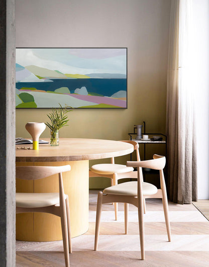 May include: A modern dining room featuring a large, round wooden table with four matching chairs. An abstract landscape painting hangs above the table. The room has a neutral color palette with a patterned floor and a sheer curtain.