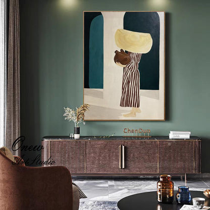 May include: An abstract painting depicts a figure carrying a large, yellow object and a brown vessel. The figure is dressed in a striped dress. The artwork is framed and hangs on a green wall. The painting is part of a home decor setting.