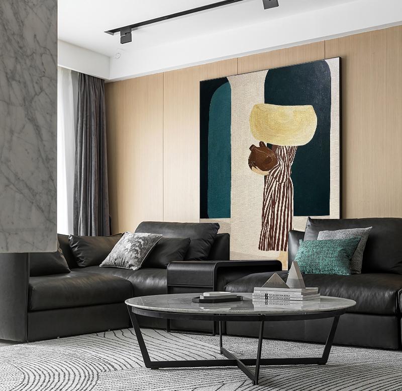 May include: An abstract painting with a beige background, featuring a dark teal archway and a dark navy blue shape. The central figure has a striped brown and white body, holding a yellow shape and a brown object. The room has black leather sofas and a round coffee table.