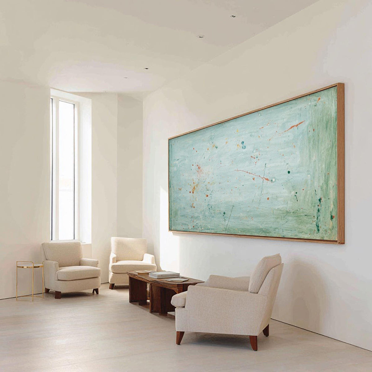 May include: An abstract painting in a light blue and green color palette hangs on a white wall. The artwork is framed in a natural wood. Three cream-colored armchairs and a wooden coffee table are in front of the painting.