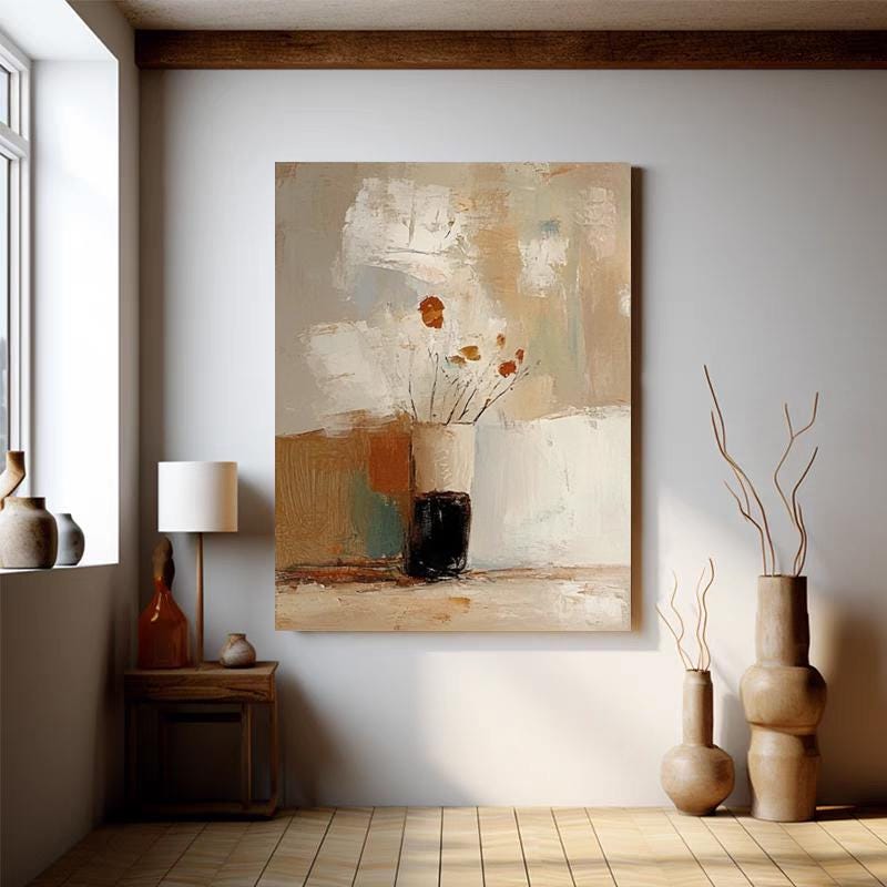 May include: Abstract art print featuring a neutral color palette with beige, brown, and white tones. The artwork depicts a vase with flowers. The painting is displayed in a room with a wooden floor and a side table with a lamp.