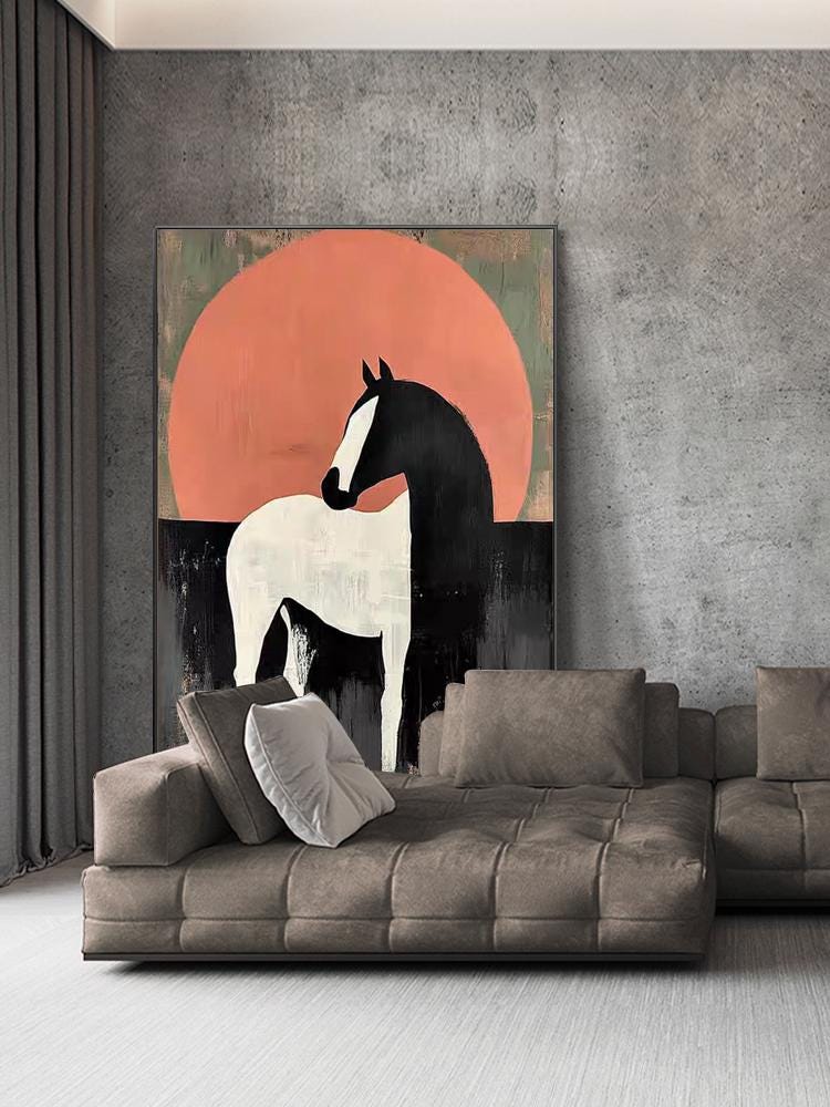 May include: Abstract painting of a horse with a black mane and white body against a peach-colored sun. The artwork is displayed above a brown sectional sofa with several pillows. The background is a gray concrete wall.