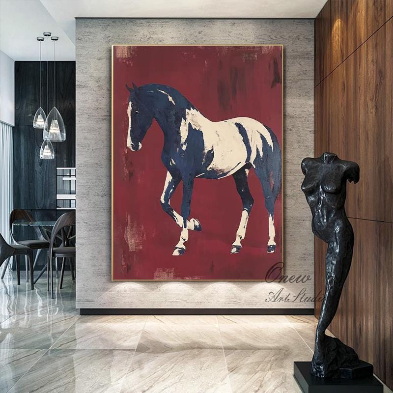 May include: Large abstract painting of a horse in navy blue and white against a deep red background. The artwork is framed in gold and hangs on a gray wall. A black sculpture of a torso stands nearby.