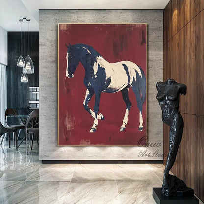 May include: Large abstract painting of a horse in navy blue and white against a deep red background. The artwork is framed in gold and hangs on a gray wall. A black sculpture of a torso stands nearby.