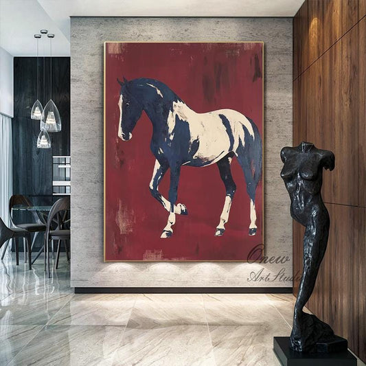 May include: Large abstract painting of a horse in navy blue and white against a deep red background. The artwork is framed in gold and hangs on a gray wall. A black sculpture of a torso stands nearby.
