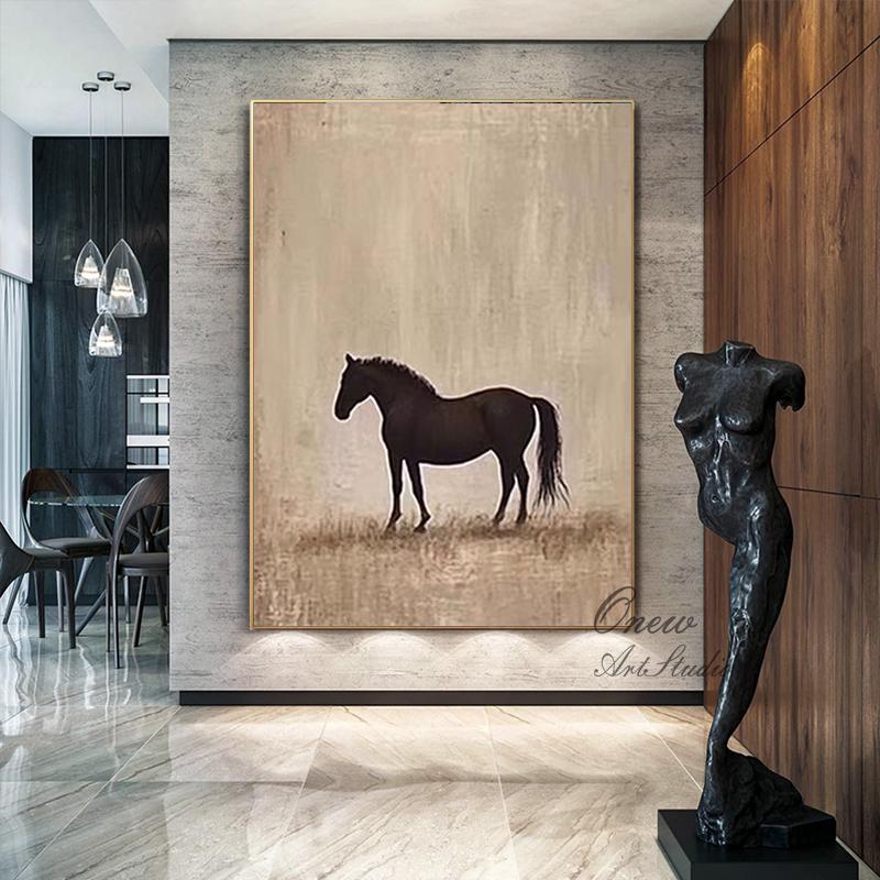 May include: A framed abstract painting of a black horse silhouette on a beige background. The artwork has a gold frame and is displayed in a modern interior. A dark sculpture of a torso is on the right.