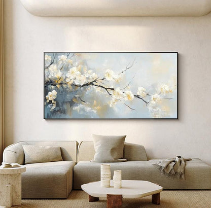 May include: A rectangular framed painting depicts a branch of white blossoms against a soft, blended background of blues, grays, and yellows. The artwork is displayed above a modern gray sectional sofa, enhancing the room's decor.