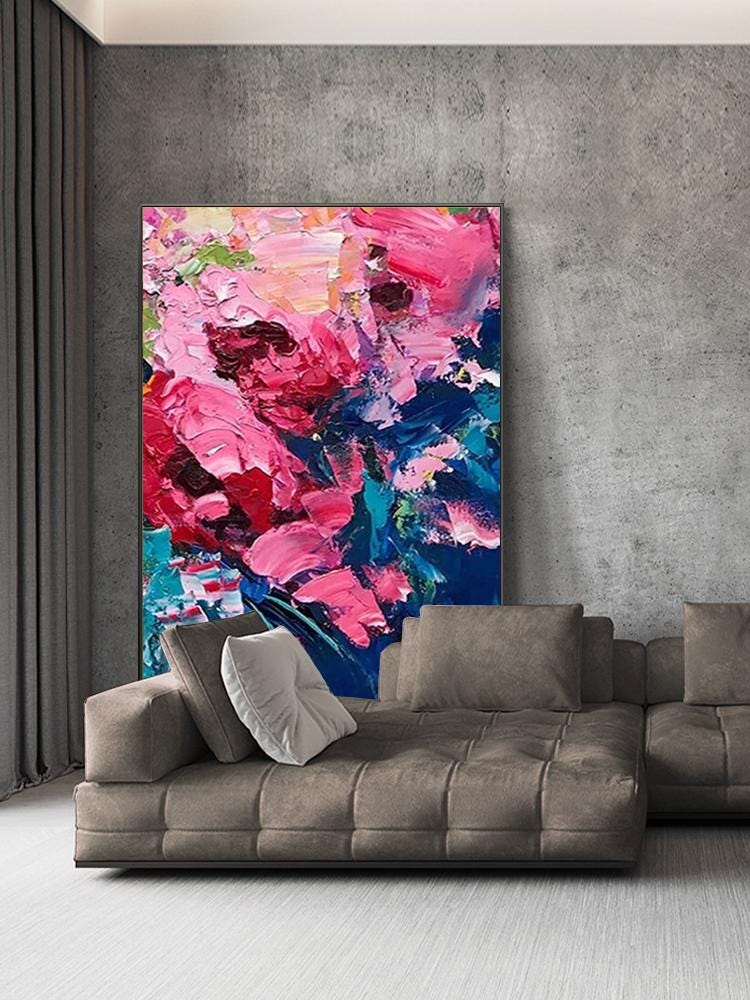 May include: Large abstract painting with vibrant pink, red, and blue brushstrokes. The artwork is displayed on a gray wall above a brown sectional sofa with several pillows. The painting's colors create a focal point in the room.