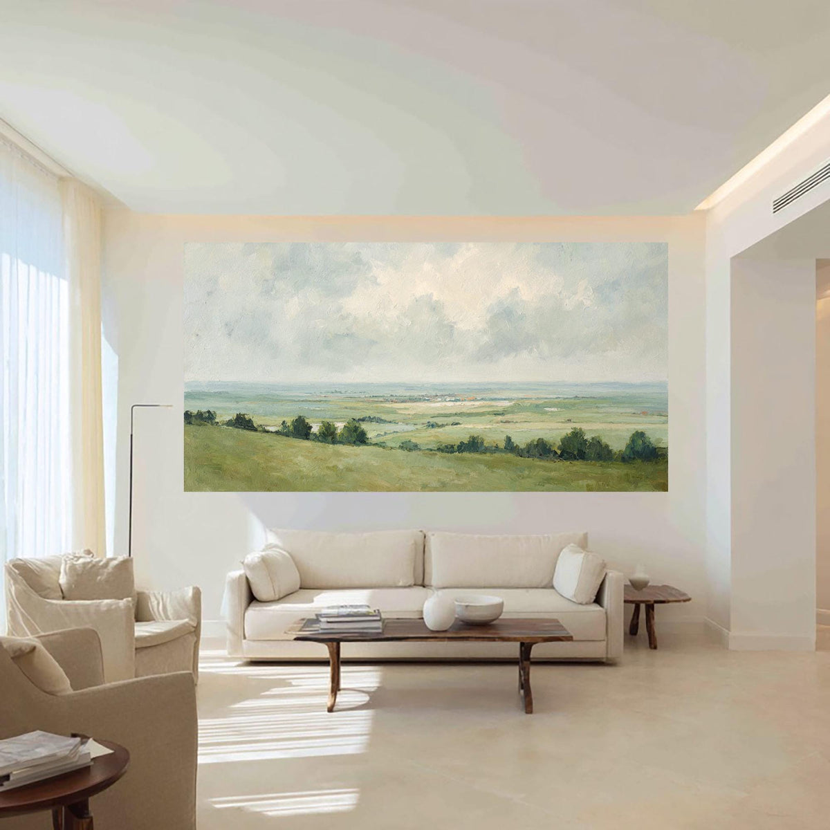 May include: A large landscape painting depicting a serene vista of rolling green hills, trees, and a distant body of water under a cloudy sky. The artwork is mounted on a white wall in a modern living room setting.