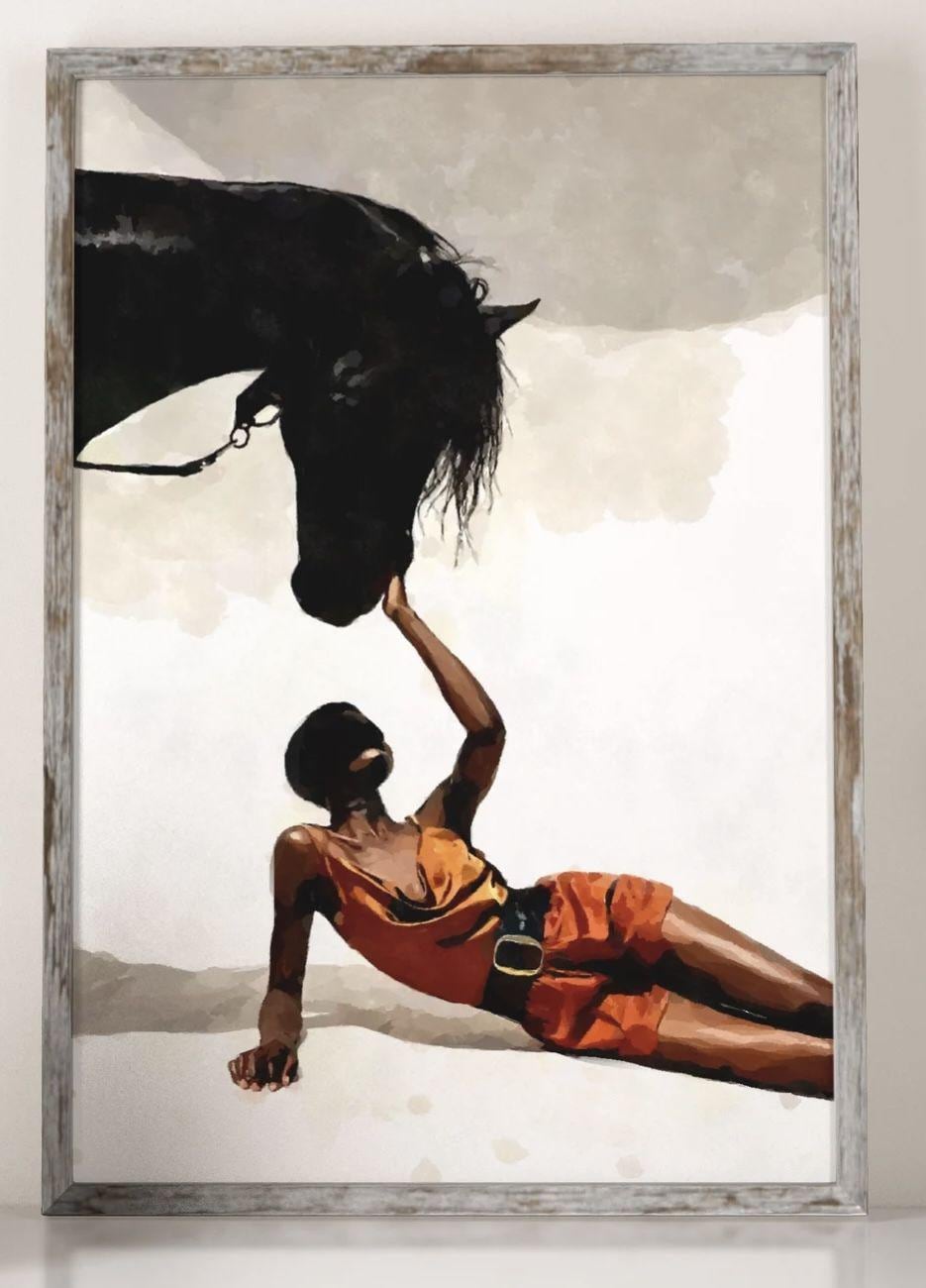 May include: Art print of a black horse and a person in orange clothing. The person is lying down, reaching up to touch the horse's head. The horse is black, and the background is a neutral color. The artwork is framed.