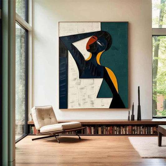 May include: Abstract painting featuring a stylized figure with a black head and body, red face, and yellow accents. The artwork is divided into white and teal sections, framed in a wooden border. The painting hangs above a bookshelf and a modern chair.