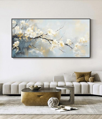 May include: An abstract painting of white blossoms on dark branches against a soft blue and yellow background. The artwork is framed in a black rectangular frame, suitable for home decor. The painting evokes a sense of tranquility.