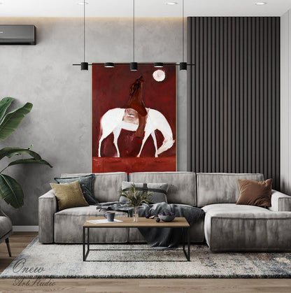 May include: An abstract painting depicts a figure on horseback with a white horse against a deep red background. The artwork, with a minimalist style, features a full moon and is displayed above a gray sectional sofa in a modern living room setting.
