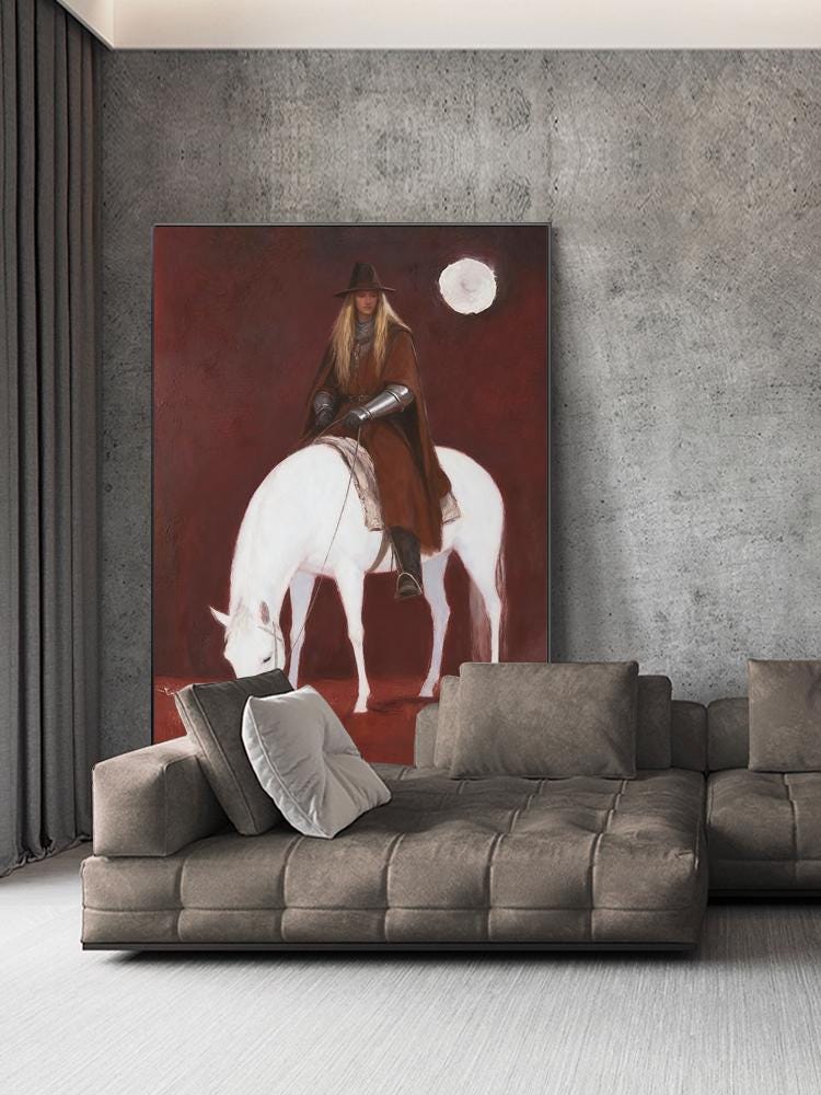May include: A large canvas painting depicts a person in brown riding a white horse under a full moon. The background is a deep red. The person wears a hat, cape, and armor. The painting is displayed above a brown sectional sofa with pillows.