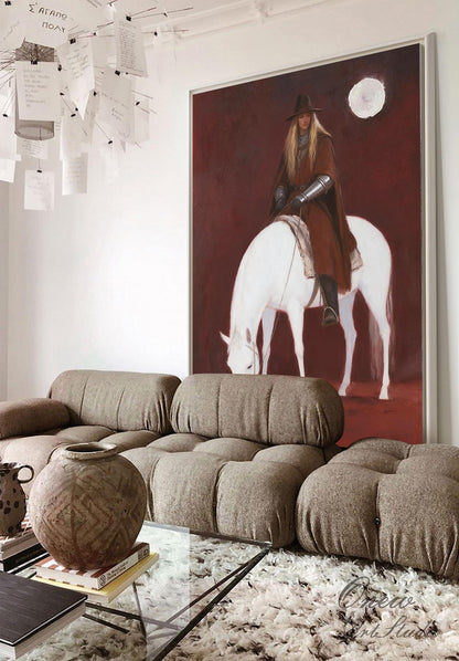 May include: A large framed painting depicts a person in a hat and cloak riding a white horse against a dark red background. The painting is displayed above a brown sectional sofa and a glass coffee table.