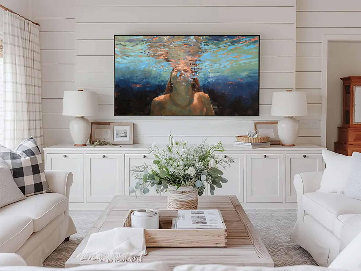 May include: Living room with white sofas, a wooden coffee table, and a large painting above a white cabinet. The painting depicts a person underwater. Two white lamps sit on the cabinet, and a vase of flowers is on the coffee table.