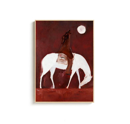 May include: An abstract painting of a cowboy on a white horse under a full moon. The cowboy is wearing a brown coat and hat. The background is a deep red color, and the painting is framed in a light wood.