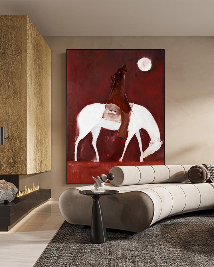 May include: Abstract painting of a rider on a white horse against a deep red background. The rider is depicted in brown, with a full moon in the upper right corner. The artwork is framed and displayed in a modern living space.