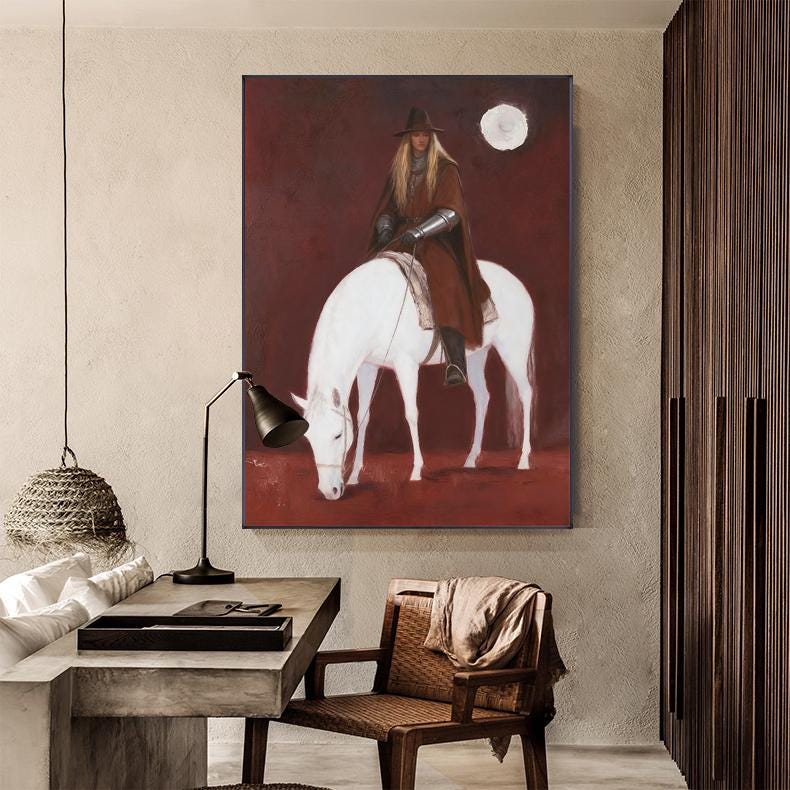 May include: A framed painting depicts a person on a white horse against a deep red background. The person wears a brown cloak, hat, and armor. A full moon is visible in the upper right corner. The horse is grazing, and the painting has a medieval theme.