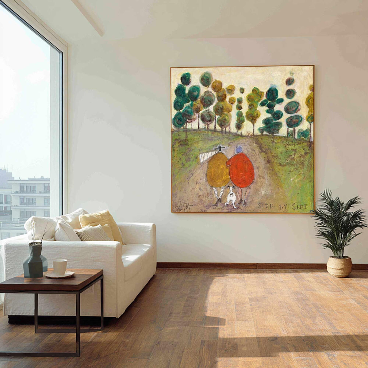 May include: A square painting titled Side by Side featuring two figures in yellow and red coats walking with a small dog on a dirt path through a green landscape with stylized trees. The artwork is displayed on a wall above a white sofa.