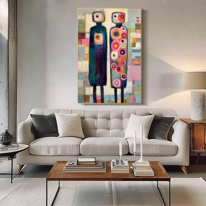 May include: A rectangular wall art piece featuring two stylized figures standing side by side. The left figure is dark teal with a central orange circle, while the right figure is light blue with numerous colorful circles in pink, red, and orange.