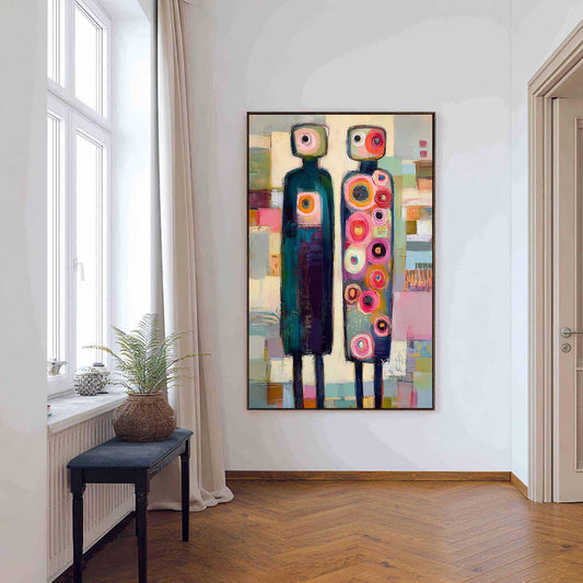 May include: A rectangular wall painting featuring two stylized, tall, thin figures standing side-by-side. The left figure is dark teal with a single circular chest detail, while the right figure is covered in numerous colorful, concentric circles.