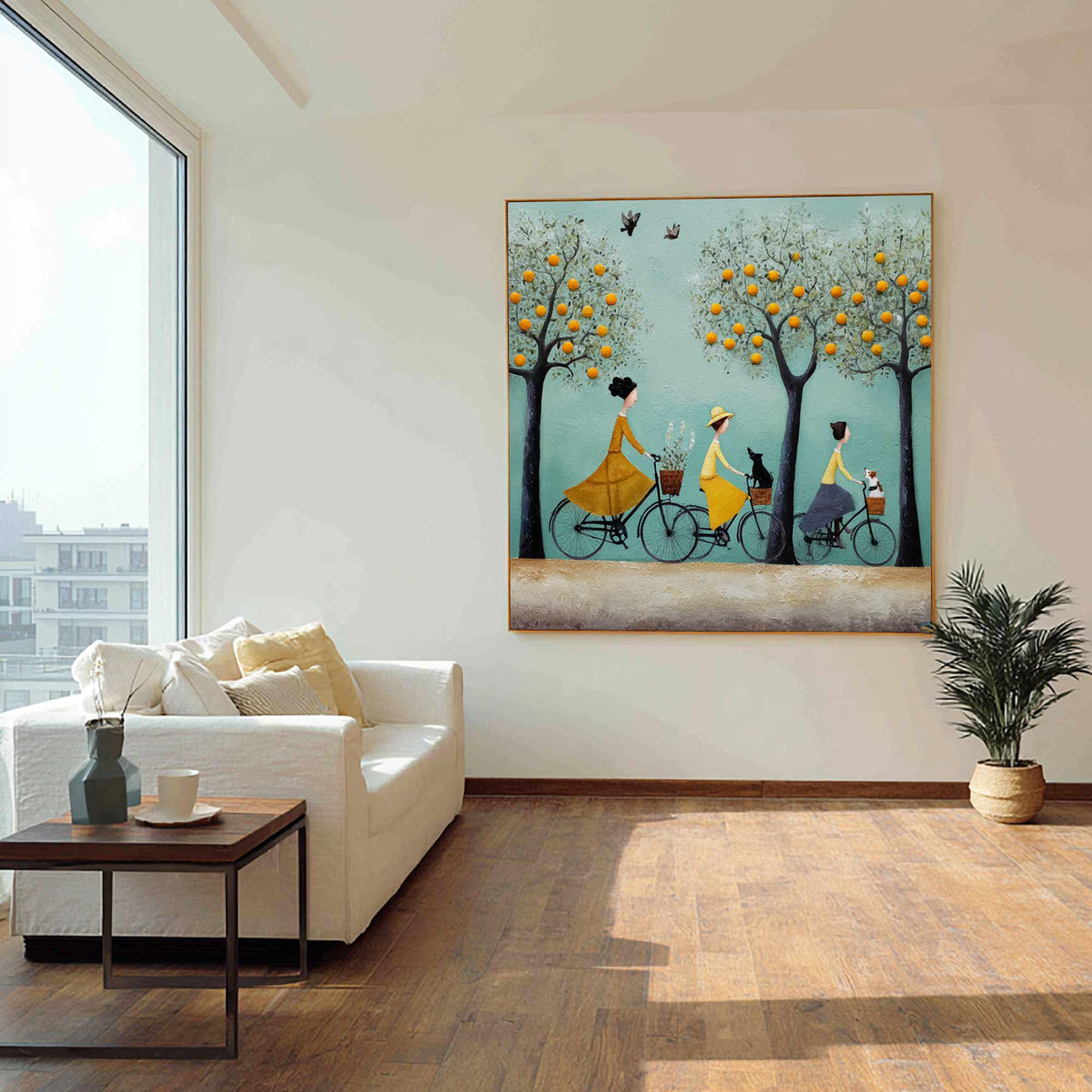 May include: A framed wall art print depicts three figures riding bicycles along a path. The figures are wearing yellow dresses and hats, with trees laden with orange fruit. A black cat and a white dog are in the baskets. The background is a light blue.