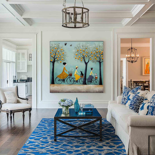 May include: A large framed painting depicts three figures riding bicycles under orange-laden trees. The figures wear yellow, and blue clothing. The painting hangs above a blue coffee table and rug in a living room setting.