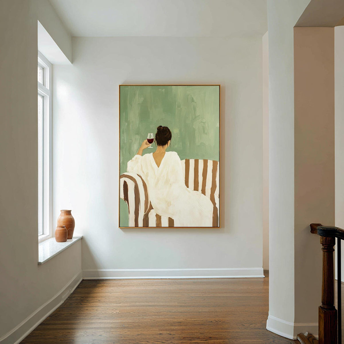 May include: An art print depicts a person in a white dress seated on a striped sofa, holding a glass of red wine. The background is a muted green, and the artwork is framed in gold. The scene evokes a sense of relaxation and leisure.