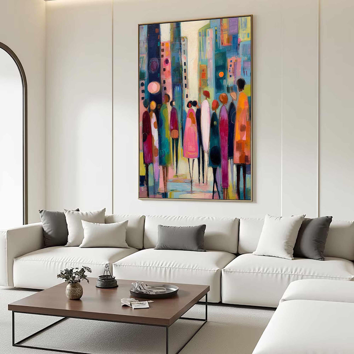 May include: Abstract cityscape painting with a gold frame. The artwork features a colorful depiction of a city street with stylized figures in various colors, including pink, orange, and blue. The painting hangs above a white sectional sofa.