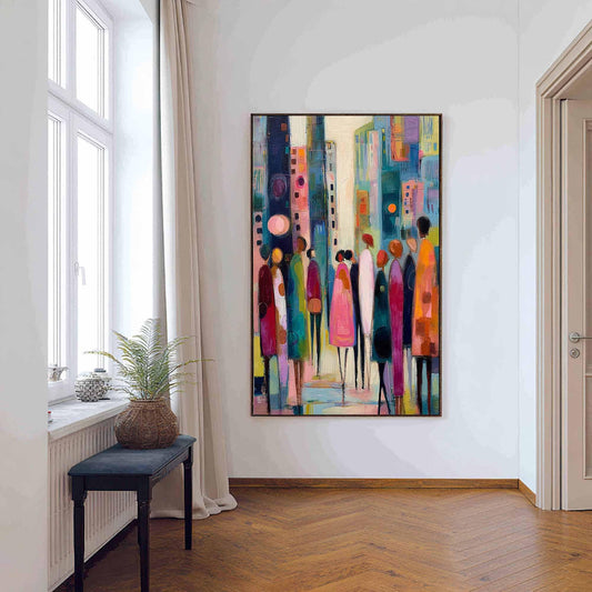 May include: Abstract cityscape painting with a black frame. The artwork features stylized figures in various colors, including pink, green, and orange, set against a backdrop of buildings in shades of blue and yellow. The painting evokes a sense of urban life and community.